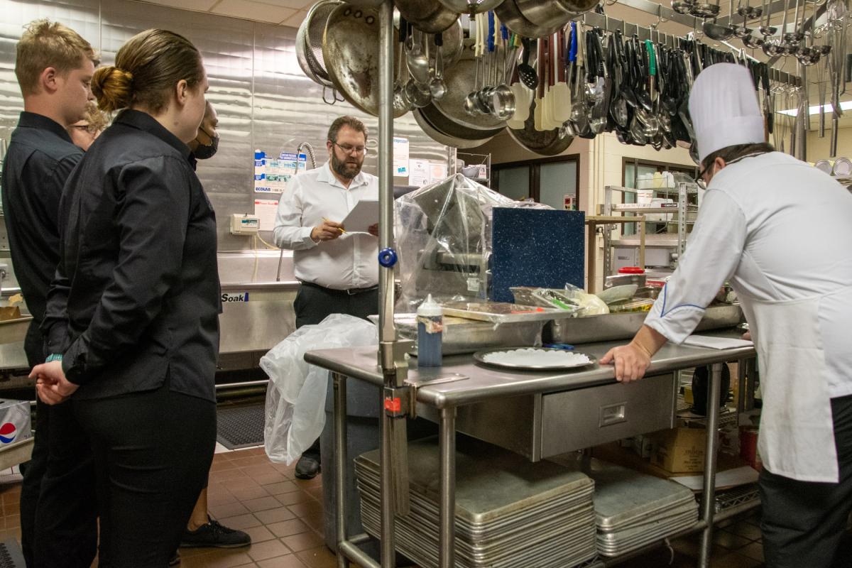 Blake E. Lambert (center), maître d’ hotel I, provides instruction for hors d’oeuvre service with students Maggy R. Langendoerfer, of Waymart; Gray; and Erutefe Agbiro, of Chester – all students in culinary arts technology. On right is Chef Mike S. Dinan, sous chef for Le Jeune Chef Restaurant.