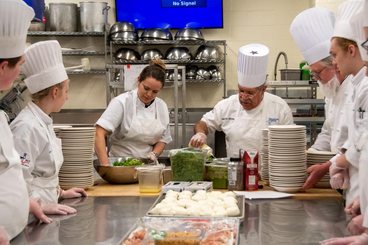 Wisneski works alongside a key mentor: Chef Michael A. Ditchfield, instructor of hospitality management/culinary arts, to toss salad greens for the first course.