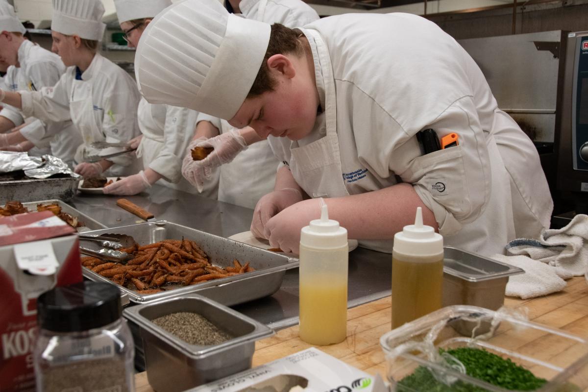 Austin D. Schlegel, of Honey Grove, carefully adds carrots to a plate. Austin is majoring in culinary arts technology.