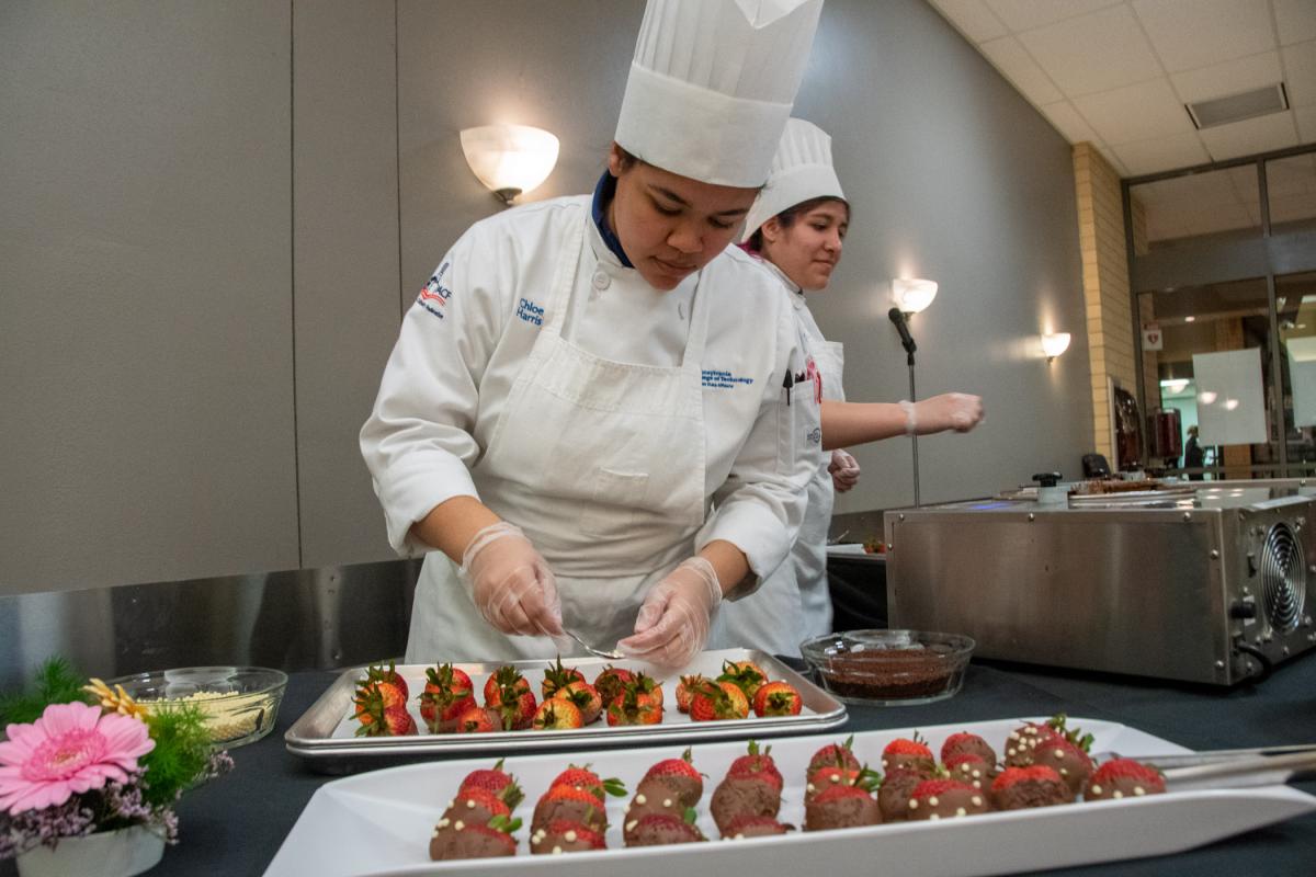 Baking & pastry arts student Chloe M. Harris, of Williamsport, dips strawberries in milk chocolate for guests at the post-dinner dessert buffet.