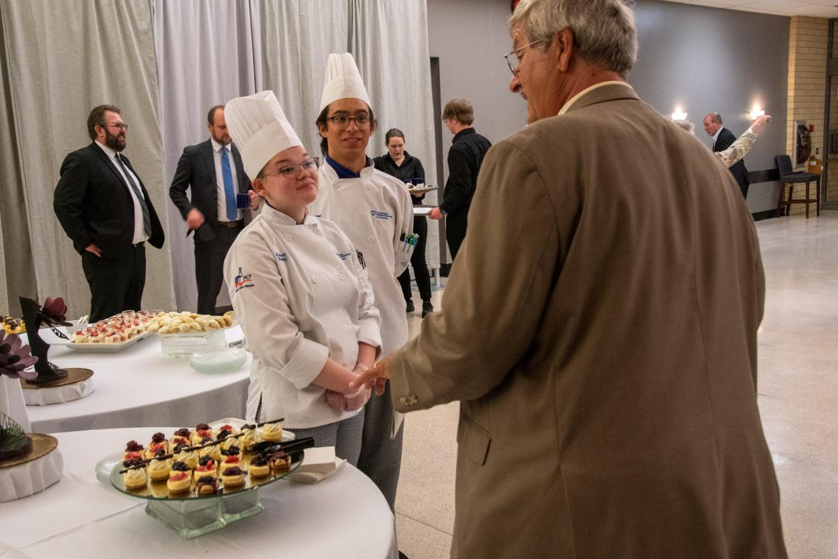 Chef Paul E. Mach, retired assistant professor of hospitality management/culinary arts, offers words of encouragement to baking & pastry arts students Autumn B. Stanley, of Lincoln University, and Macdonald. After working dozens of Visiting Chef events behind the scenes, Mach returned as a guest to enjoy the work of his former student.
