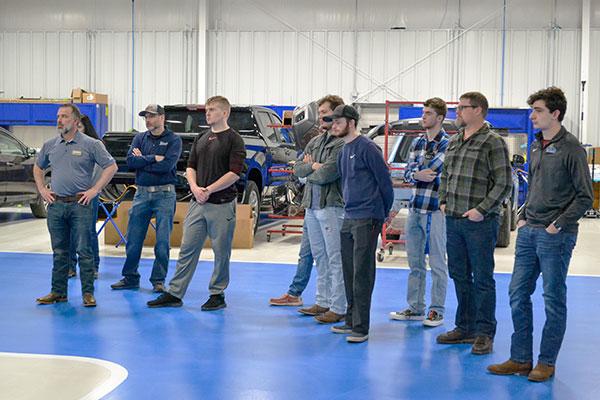 Collision repair instructor Loren R. Bruckhart (second from right) and students listen as employees introduce themselves in the state-of-the-art collision facility in Montoursville. At left is Adam Alexander, vice president of Blaise Alexander Family Dealerships.