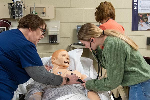 With nursing instructor Ann E. Morrison, Natalie Eckeberg-Timoney listens to the heart and lung sounds within SimMan’s chest.