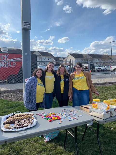 Friendly faces bring information and intention to a game-day tailgate. From left are Nat G. Santaella, coordinator of student engagement; Meghan R. Delsite-Coleman, assistant director of student engagement; Calli R. Ackels, wellness education coordinator (who provided the photo); and Savannah J. Zook, a human services & restorative student and student engagement intern.