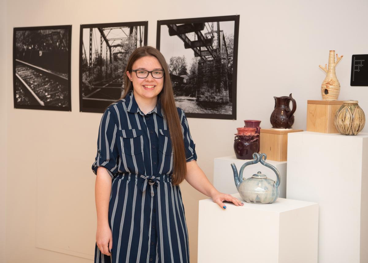 Alexis M. Burrell, of Danville, a senior in graphic design at Pennsylvania College of Technology, is seen in the lobby of The Gallery at Penn College, where her ceramics and photography exhibit – “Moving the Earth, Capturing the Sun” – is on display. 