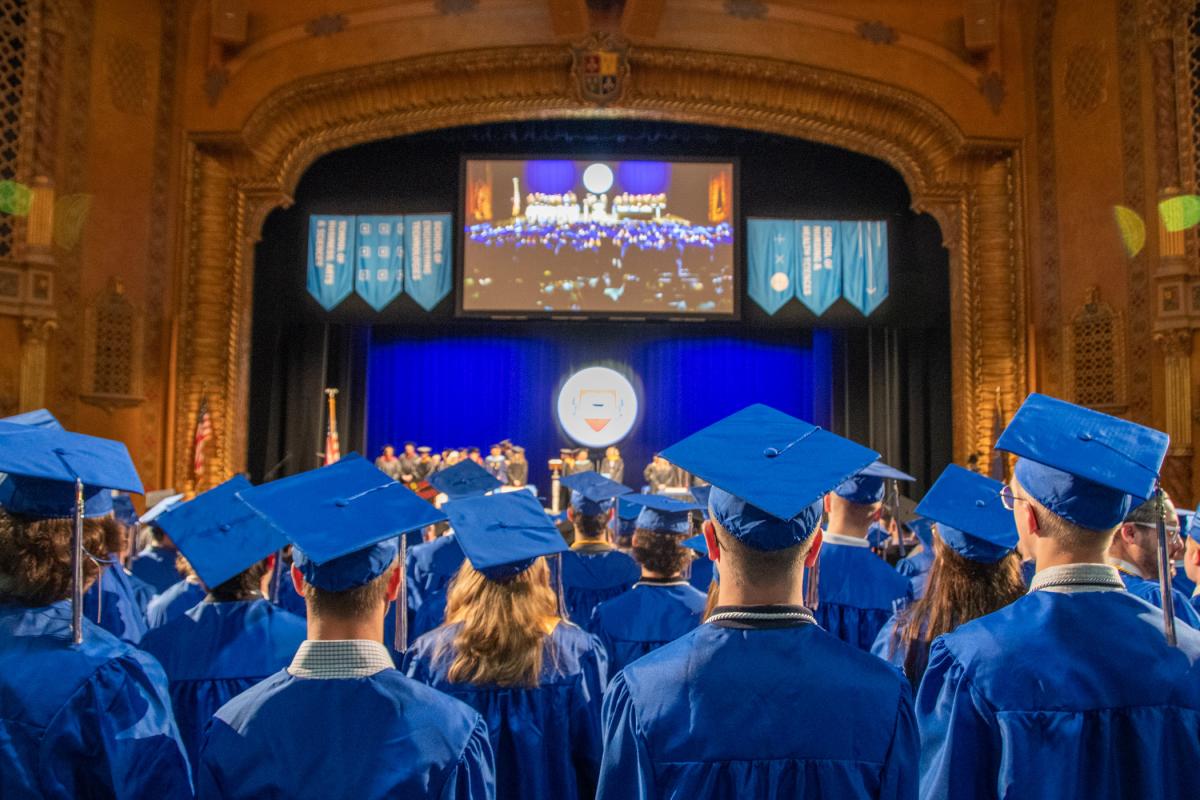 Grads remain standing as they watch members of the platform party – beloved faculty among them – process to the stage.