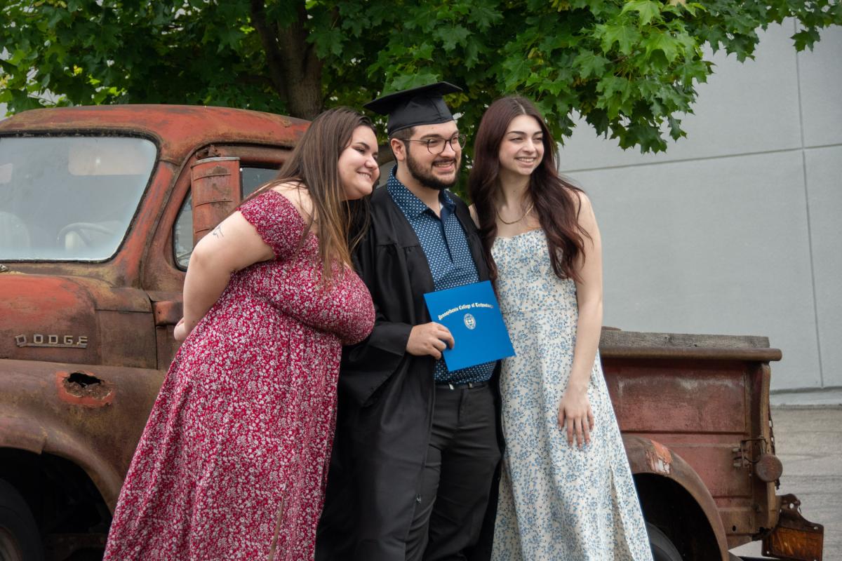 Automotive technology management grad Nicholas G. Leonard commemorates the occasion with the college’s truck fountain; his girlfriend, Adrianna E. Abate (left), a student in allied health; and his sister Juliana.
