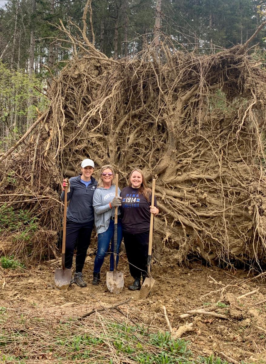 Victoria Hurwitz joins students Landis and Bennett in front of the enormous root system of a fallen tree.