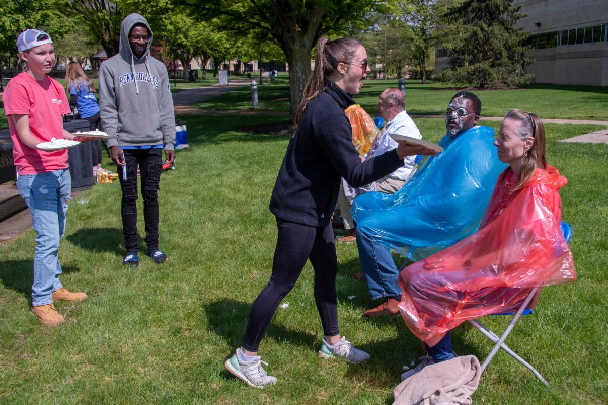 As Business Club members Alicia M. Wyland (left), business administration: sport & event management concentration; and Samir K. Pringle, business administration, stand ready with more pies, Rich braces for an attack by her daughter Ashley, who drove from Lock Haven for the occasion. 