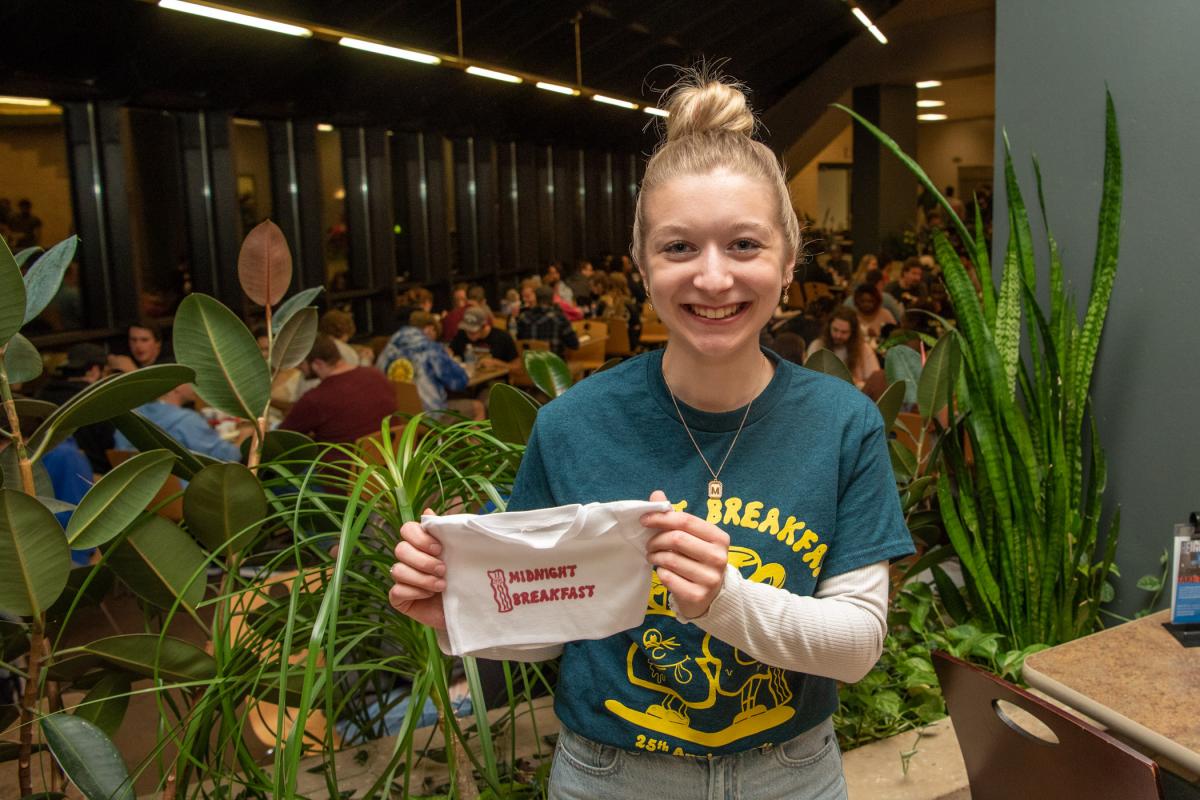 The designer of the Midnight Breakfast T-shirts: Melina K. Petrick, a dental hygiene student from Falls Creek! (Behind her, the KDR atrium teems with enthusiastic breakfast guests.) In addition to regular-size shirts, mini shirts were created for the stuffed-animal giveaways.