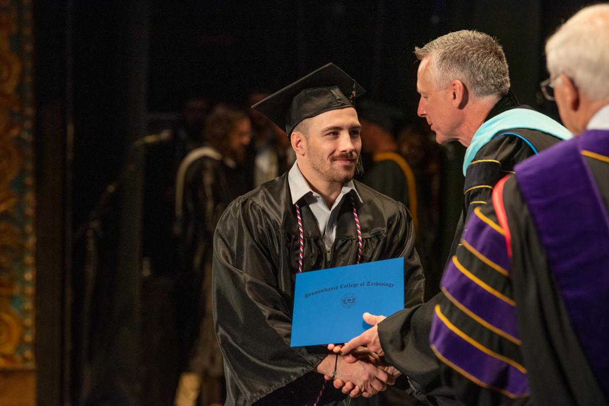 Welding & fabrication engineering technology alum Cameron J. Dickey leans in for the president's congratulatory grasp ...