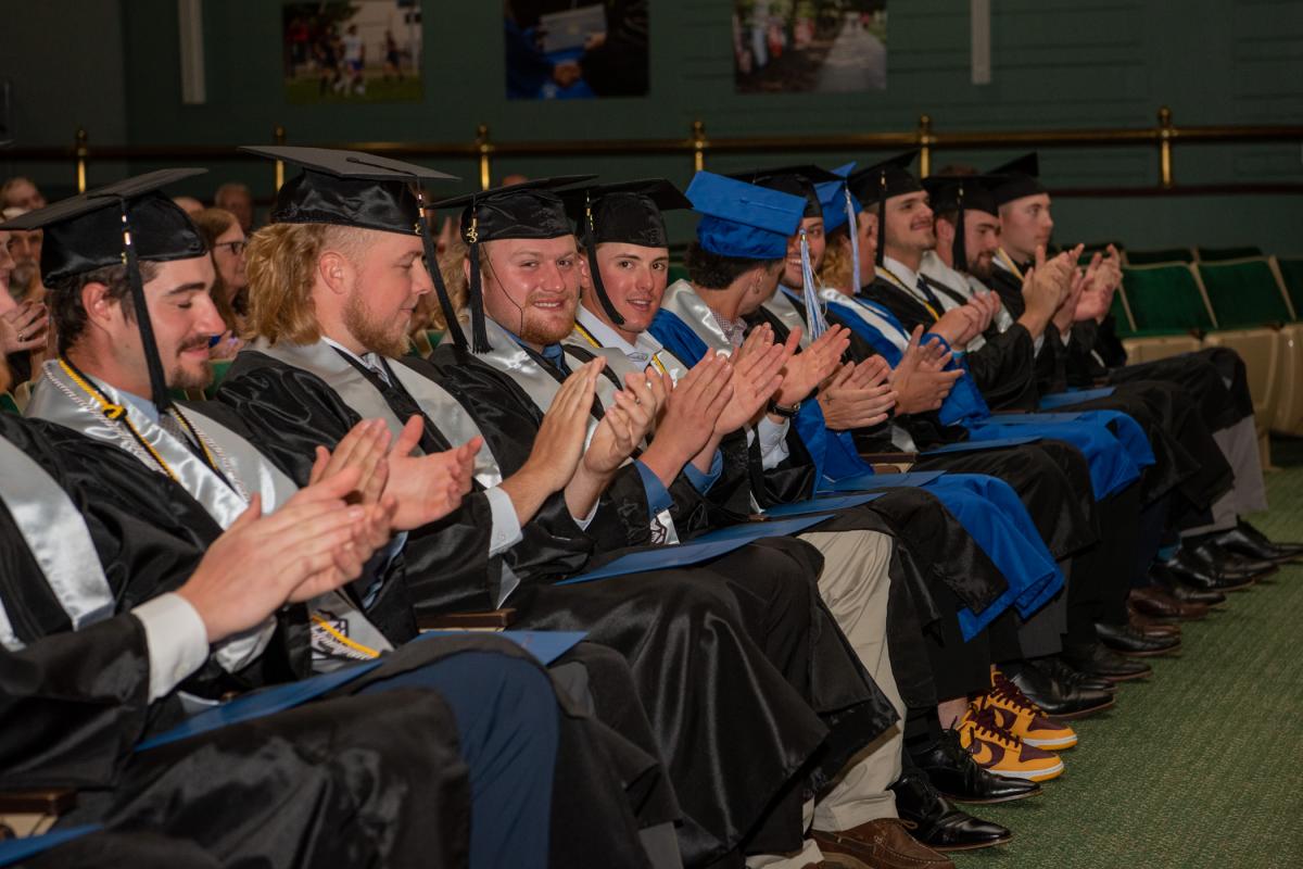 Shane D. Price (left center) and Keegan M. Nytz catch the photographer's eye while applauding the group's collective accomplishment.