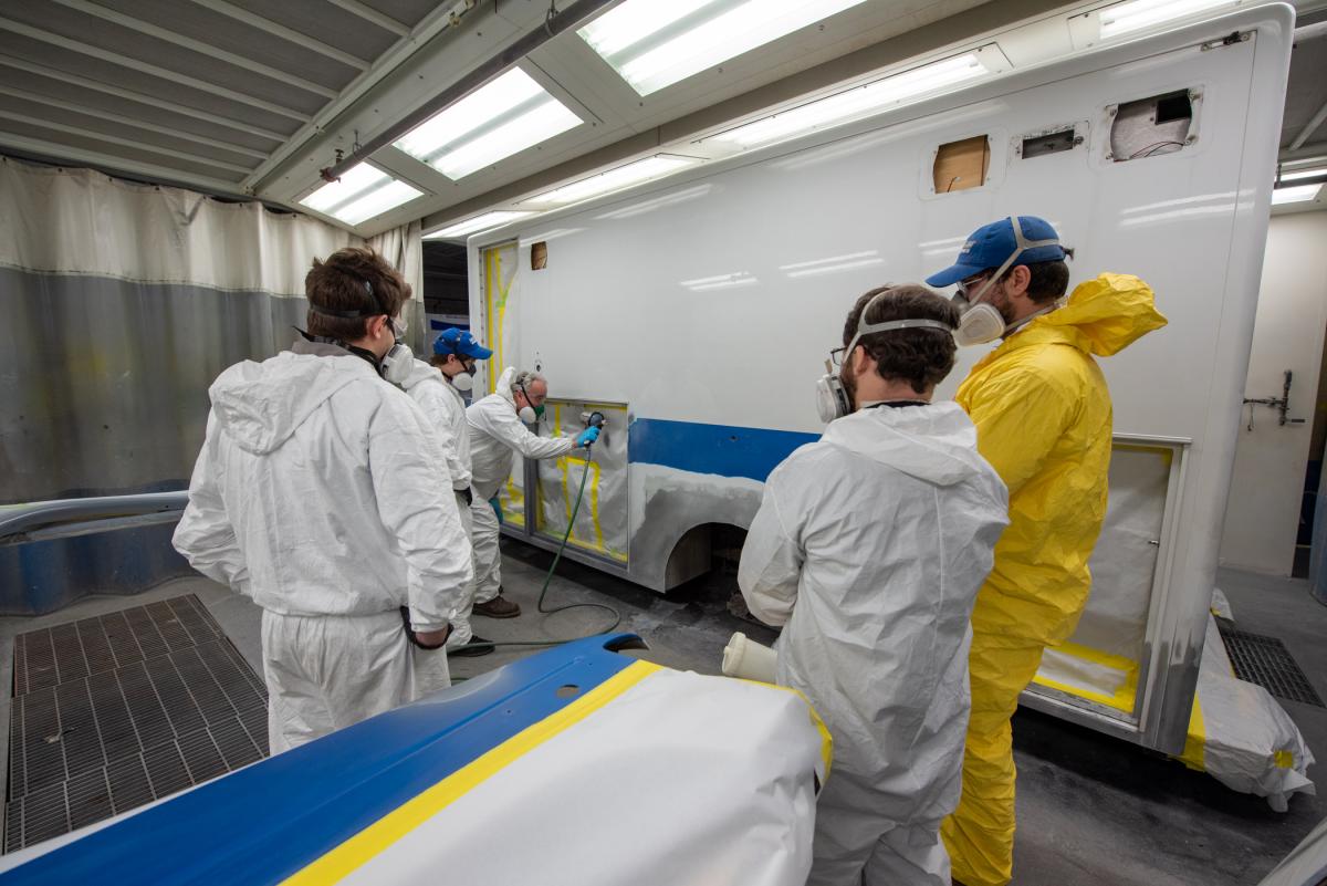 Klinger (with spray gun) preps the donated ambulance in one of the College Avenue Labs paint booths.