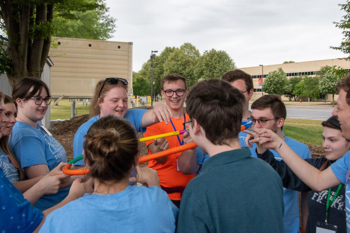 ACEE participants join student orientation leaders on the Fish Real Estate Leadership Challenge Course, where among their tasks was keeping one finger on a “helium” hoop while lowering it to the ground.
