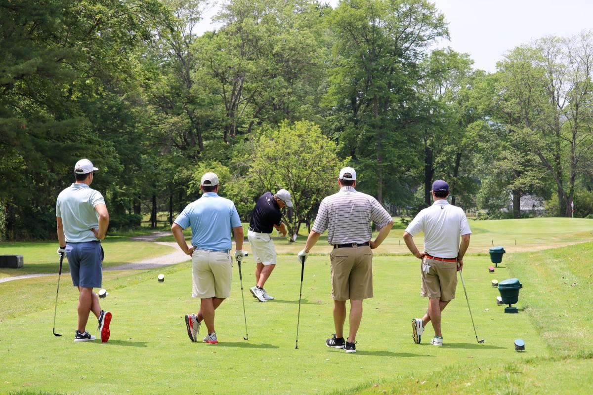 Golfers from BRIX Design Group watch the pro's tee shot.