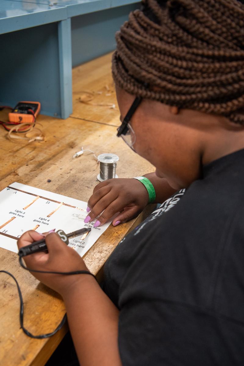 At the Lumley Aviation Center, a camper solders copper wire to create an operating circuit as part of a look into engine electrical systems.