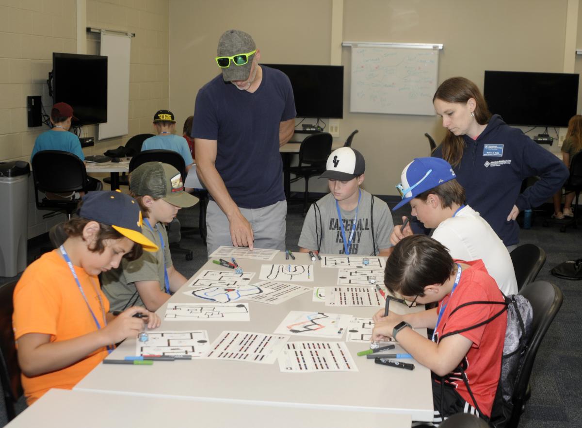 Krepshaw and Melissa A. Webb, instructor of technology and information literacy/course coordinator, guide middle school students through their coding assignment.