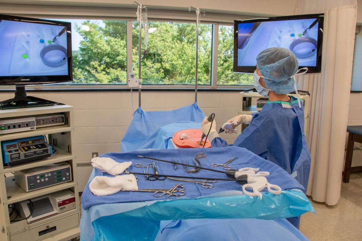 Using the tools of a laparoscopic surgeon, a participant places balls atop tubes.