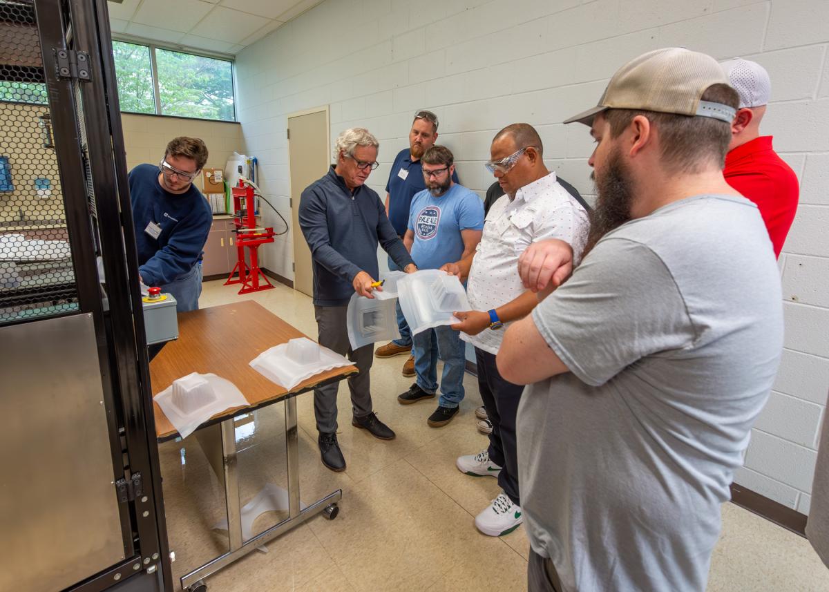 Guest instructor Mark Strachan (second from left), a nationally recognized industry expert, and workshop participants assess product as it rolls off the thin-gauge thermoforming equipment in Pennsylvania College of Technology’s Plastics Innovation & Resource Center. 