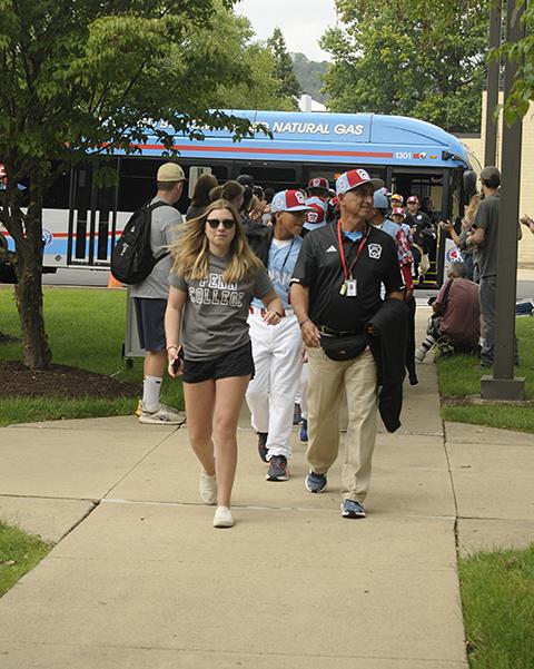 Student volunteer Kylee P. Albert, a business administration student from Boyertown, leads the Panama team from its River Valley Transit Authority bus to the picnic grounds.
