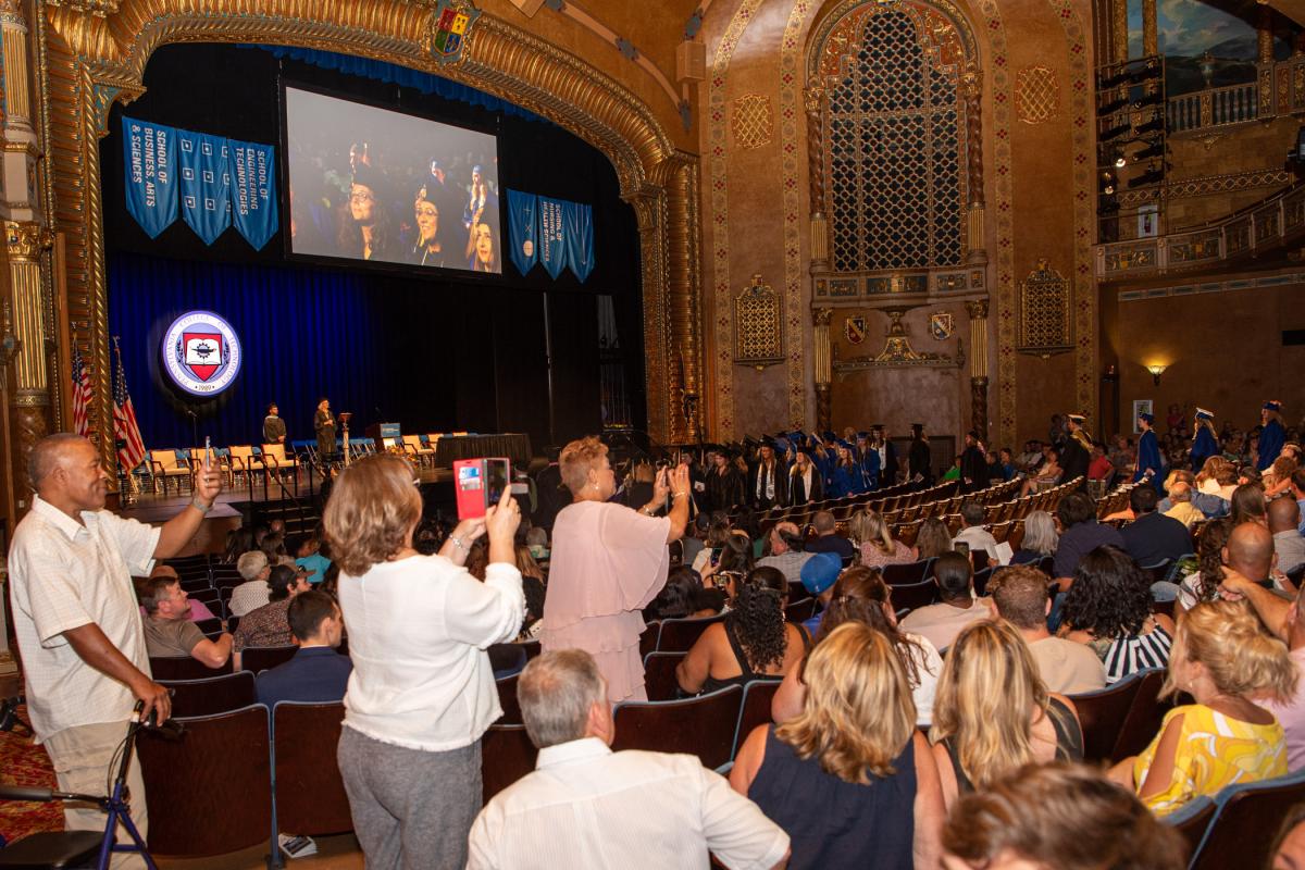 As graduates enter the glowing venue, proud family members capture the auspicious occasion.