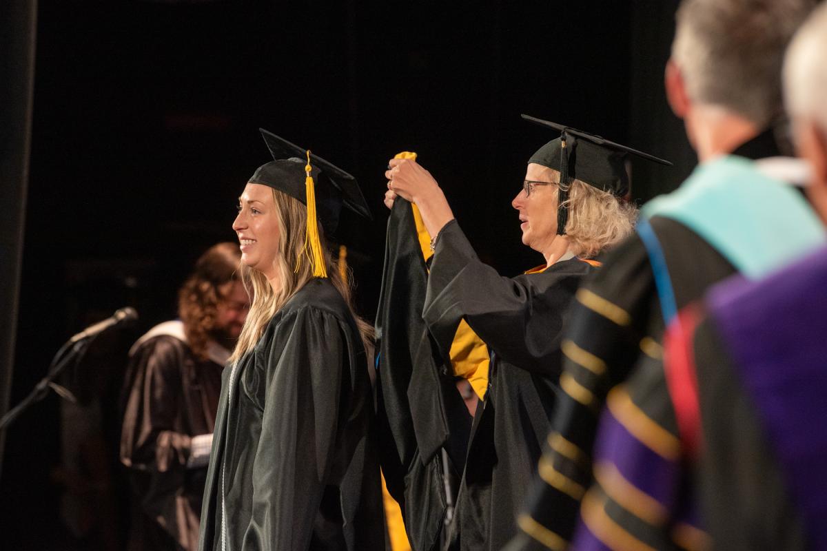 Elise Carolyn Mullen, who graduated in the combined physician assistant studies bachelor/master's degree, makes it official with help from Joanna K. Flynn, interim vice president of academic affairs and provost. 