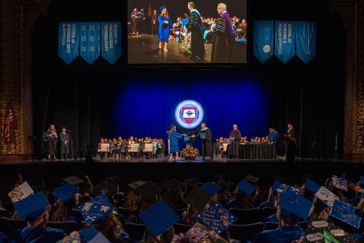 A wide shot of the stage beautifully illustrates the many hands involved in successfully commemorating student success. From left are Anthony J. Pace, dean of enrollment and academic operations; Scott A. Geist, program director, announcing the graduates in surgical technology; associate degree recipient Abby L. Underhill, honored with the Surgical Technology Outstanding Academic Achievement Award; state Sen. Gene Yaw, chairman of the college's board of directors; Jennifer McLean, dean of students; and Flynn