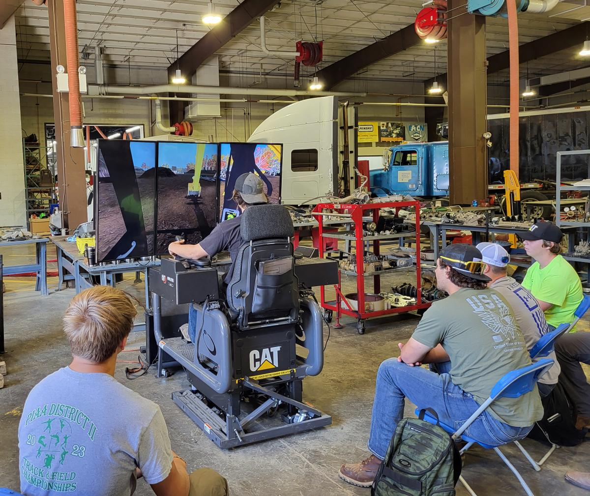 A "must-do" for students circulating among the day's many activities was this simulator from H.O. Penn. Trying his hand, while classmates await their turn at the controls, is Luke R. Klinfelter, a diesel technology student from Spring Mills.