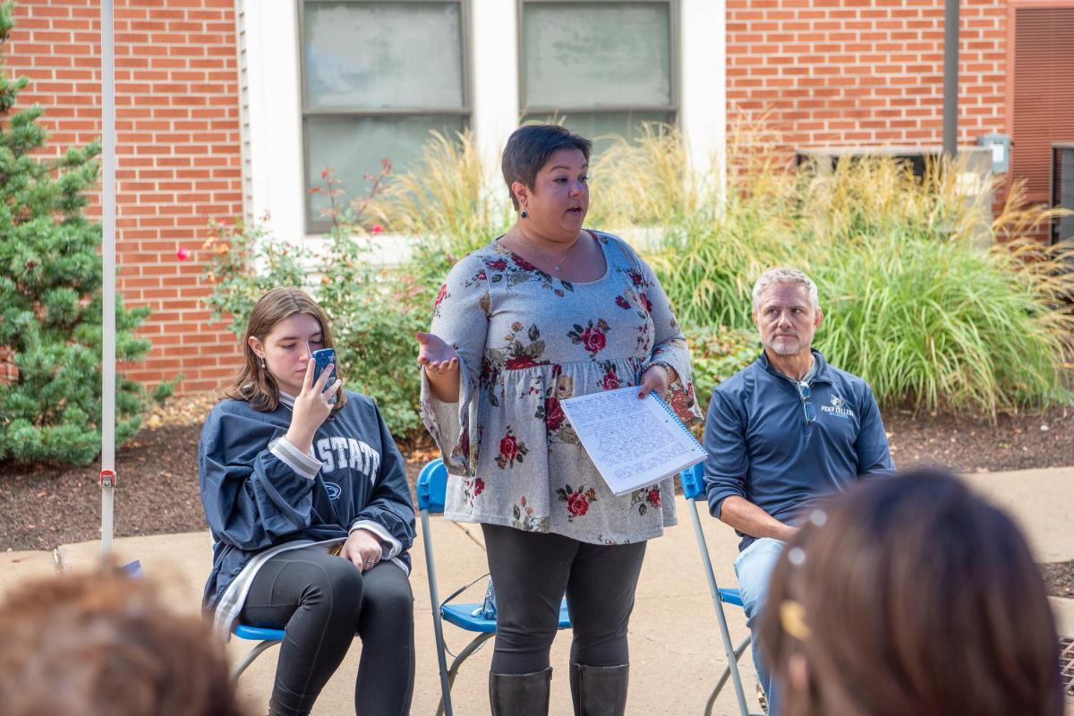 Michelle (Goddard) Hood, a member of the Village Council that created the time capsule 25 years ago, offers a student perspective as her daughter, Madison (seated at left), records the proceedings. Hood, a pre-dental hygiene student in 1997-98, resides in Harrisburg. In her address, she honored the memories of two students: Joseph DeFeo, a student who died in April 1998 and for whom the time capsule was dedicated at the time, and Deena Jean Cooper ’02, graphic design, another member of the Village Council 