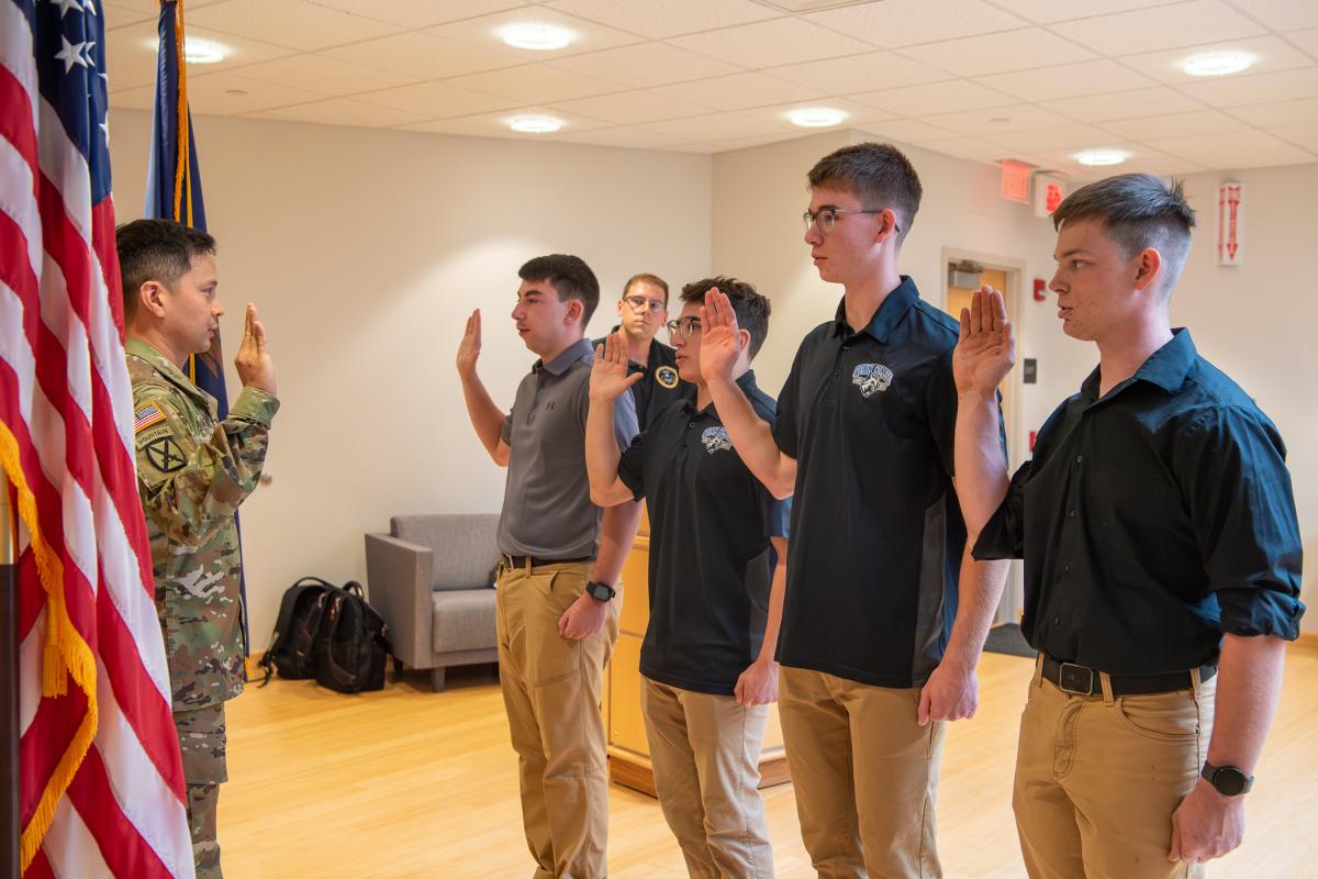 Gaitan (left) administers the oath of office to (from right) ROTC cadets Rossman, Reaugh, Coukart and Arnold. Looking on from the podium is Skylar Mincer, ROTC logistics specialist, who presided over the contracting ceremony.
