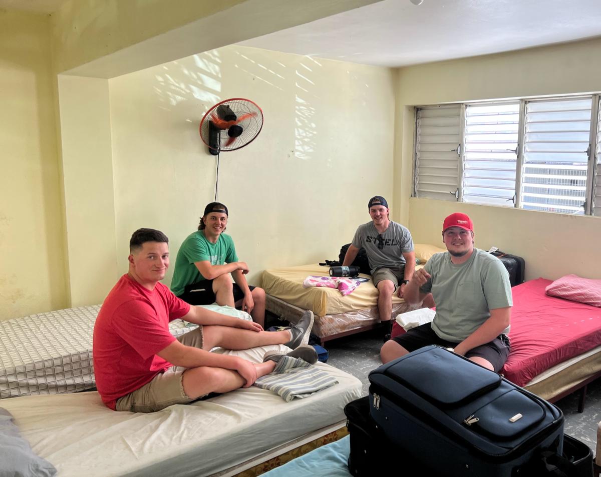 Huddled around a solitary fan on a hot first night in the Dominican Republic – and excited for the week ahead – are (from left) McAfee, Adams, Ledebohm and Mann.