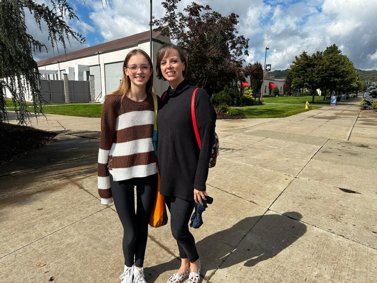 A mother and daughter on a mission happily stop on the campus mall to oblige a photographer.
