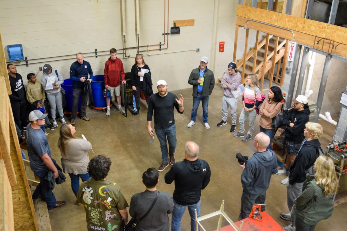 The upper floor of the HVAC lab's realistic residential lab frames this overhead overview of instructor Daniel J. Harris and Open House visitors.