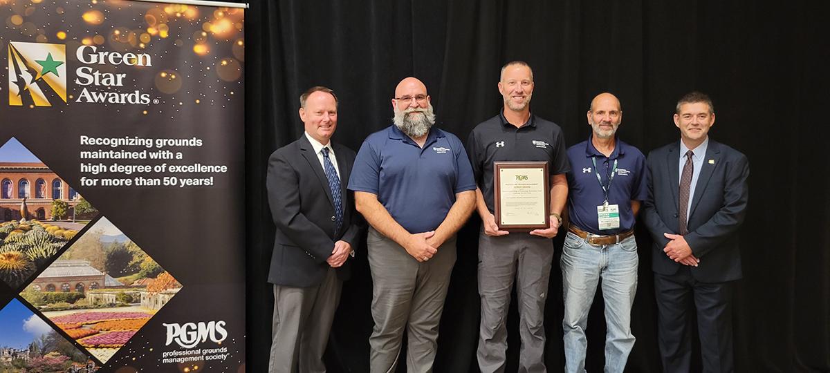 A team from General Services at Pennsylvania College of Technology accepts an Honor Award from the Professional Grounds Management Society. From left are: Jeff Schneider, chair of the PGMS Green Star Awards; Penn College General Services staff: Don J. Luke, director of facilities operations, Chad L. Karstetter, horticulturist/grounds and motorpool manager, and Brooke M. Barton, horticulturist; and Bruce DeVrou, PGMS president. 