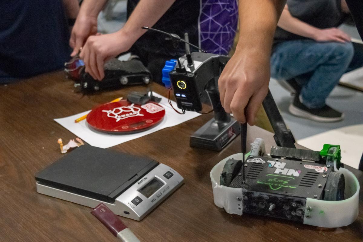 Near a scale ensuring that entrants meet their competition weight, busy hands make final adjustments.