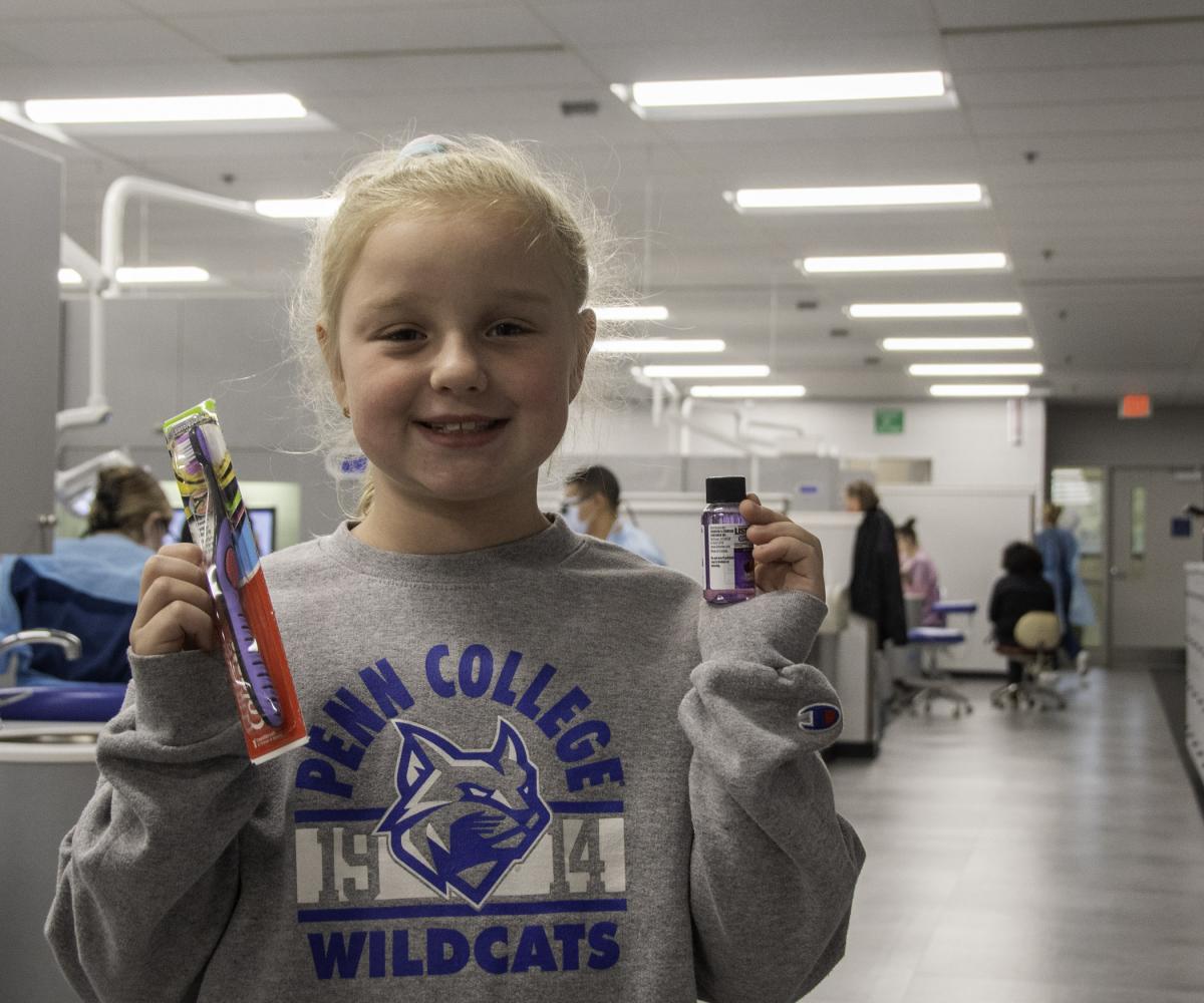 A child shows some of the contents of her “gift bag”: a new toothbrush and a bottle of mouthwash.