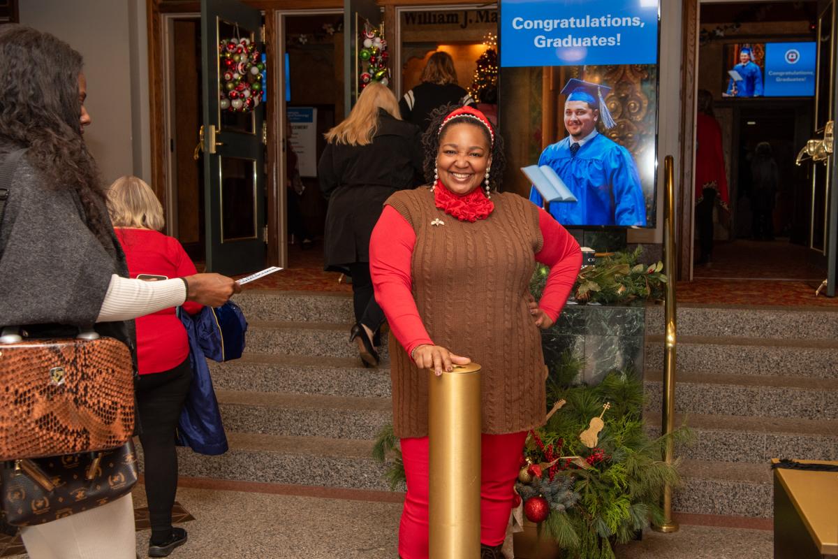 Welcoming guests (and taking their tickets) with a festive spirit is Tamaka F. Carter, financial aid assistant ...