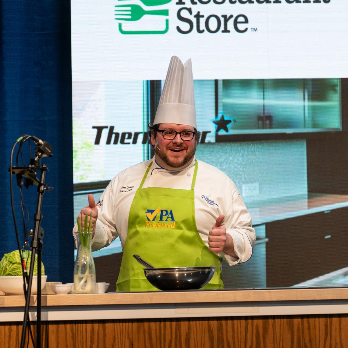 Dinan, executive chef of Le Jeune Chef Restaurant, where Penn College hospitality students practice their craft, engages the crowd as he demonstrates Korean sticky chicken with cabbage stir fry.