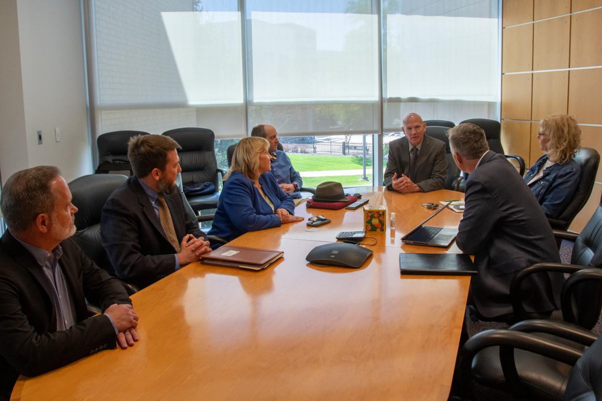 People in business clothing converse at a conference table in Penn College's Davie Jane Gilmour Center.