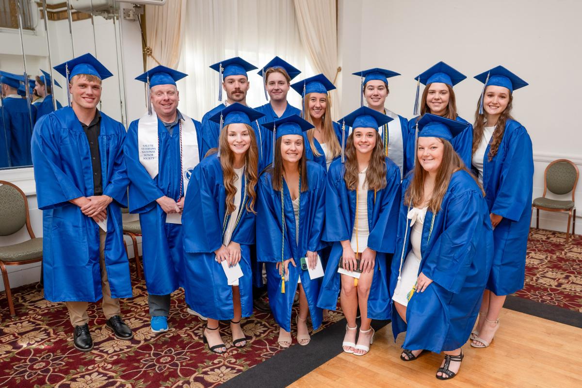 A group of men and women in blue graduation caps and gowns.