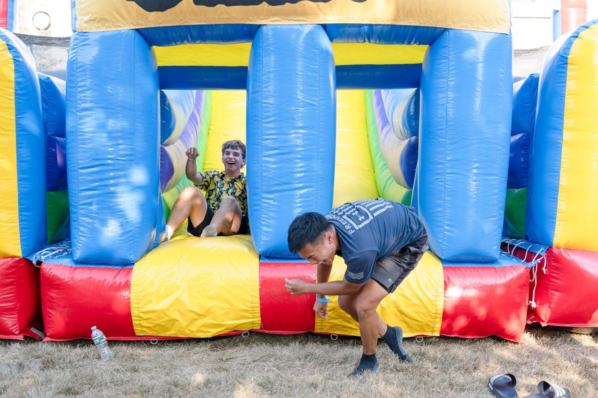 Students laugh as they exit a large inflatable sliding board.