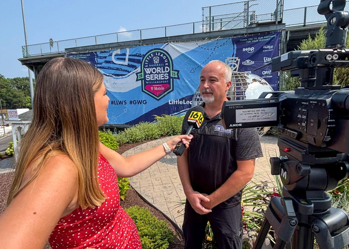 WNEP's Mackenzie Aucker holds a microphone up to Penn College automotive restoration and collision repair instructor Roy H. Klinger, who has a TV camera pointed at him.