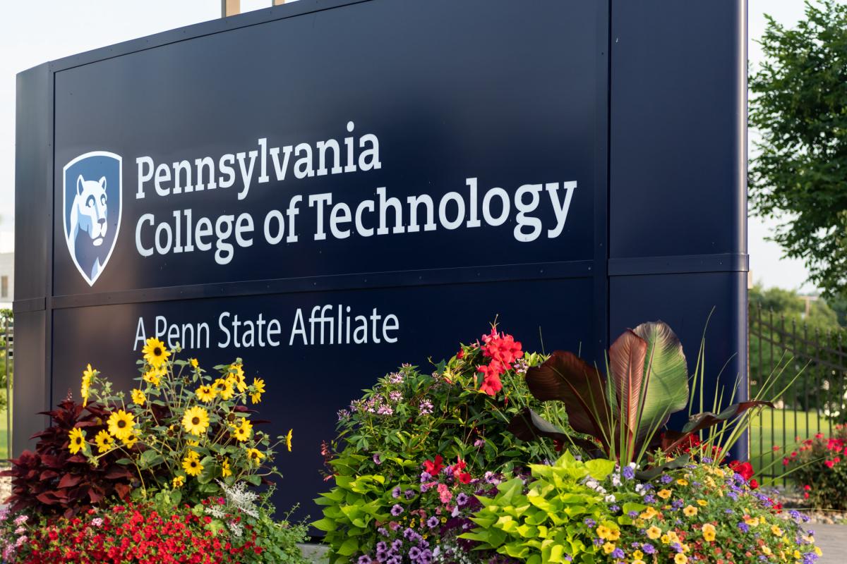 A colorful flower arrangement in front of Pennsylvania College of Technology's main entrance sign.