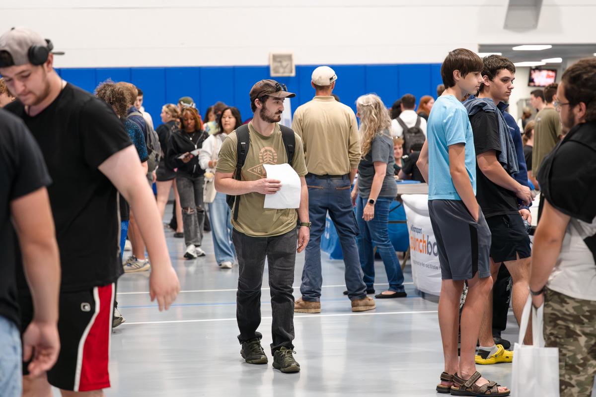 Students walk through a crowded field house.