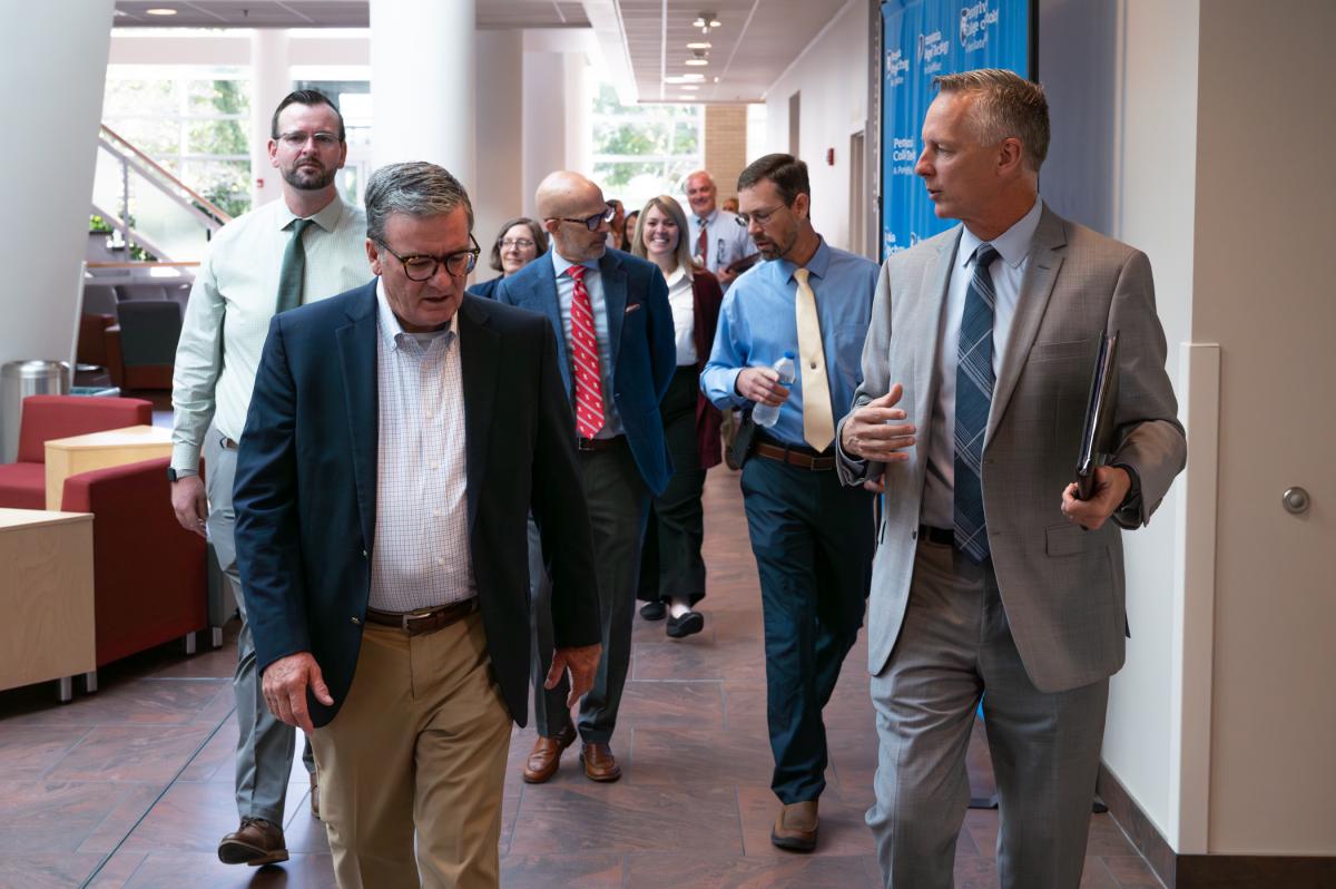 People in business attire chat while walking through Penn College's Davie Jane Gilmour Center. At the front are Pennsylvania Secretary of Transportation Michael Carroll and Penn College President Michael J. Reed.