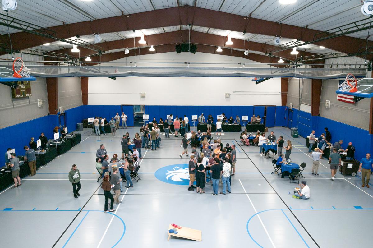 Overhead view of the Field House floor, with tables lining the edges and people gathered around round tables in the center.