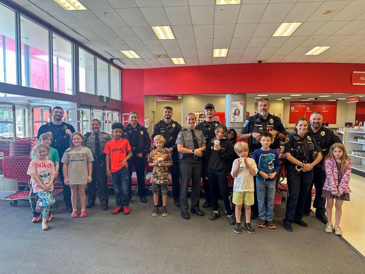 A group of children and police officers gather for a photo inside the Target store entrance.