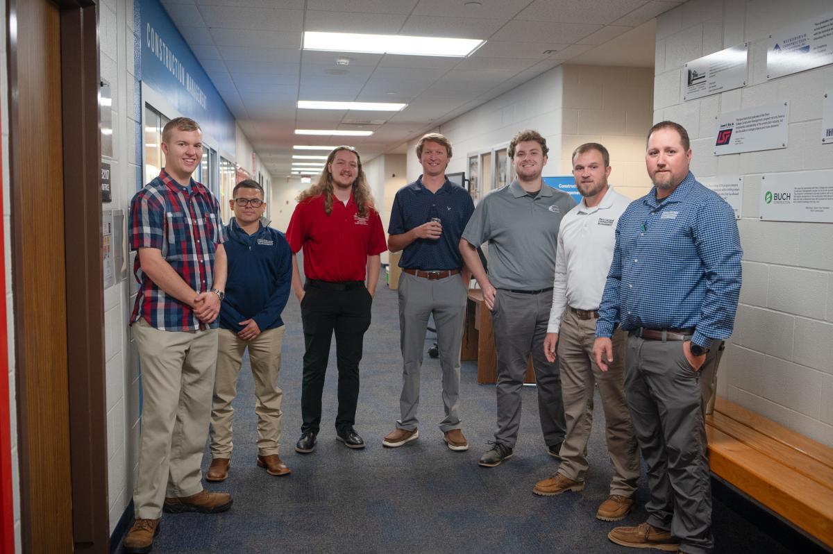 A group of students and faculty pose in a hallway.
