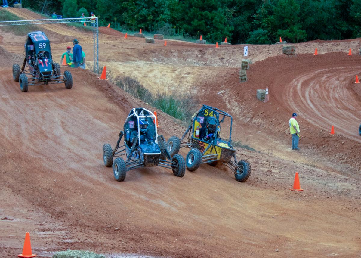 Off-road "Baja" vehicles travel over a dirt track.