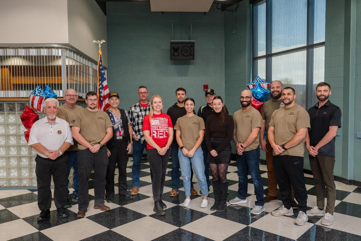 A group of people, some wearing hats or shirts that indicate their military branch.